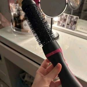 Revlon One-Step Rund Borste - Säljer en Revlon One-Step Round Brush Dryer & Styler Booster. Borsten är svart med en rosa detalj och har rund form med täta borststrån. Perfekt för att styla och torka håret samtidigt, med flera värmeinställningar. Ergonomiskt handtag och elektrisk funktion.