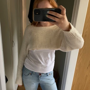 Croppad stickad tröja från Zara - Superfin croppad stickad tröja från Zara i ljus beige färg. Tröjan har långärmade, lite loose ärmar och bred halsringning. Perfekt att slänga över en t-shirt för en chill och trendig look. Passar dig som gillar att sticka ut med din stil.