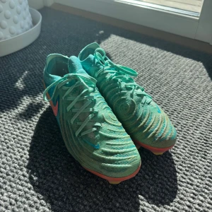 Nike Phantom turkosa fotbollsskor - Säljer ett par Nike Phantom fotbollsskor i en fräsch turkos färg. Skorna är gjorda i syntetmaterial med stickad krage för extra komfort. 