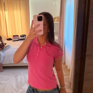 Rosa piké från Ralph Lauren - L i barnstorlek! Säljer en klassisk rosa pikétröja från Ralph Lauren med korta ärmar och krage. Tröjan har knappar framtill och den ikoniska loggan broderad på bröstet. Perfekt för dig som gillar sportig och stilren look.