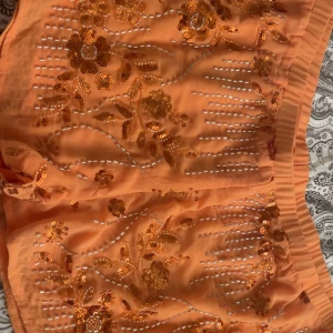PEPPERMAYO Nya Sequin Shorts - Snygga orange shorts med blommigt paljettmönster och glittriga detaljer. De har elastisk midja och är tillverkade i ett lätt, transparent syntetmaterial som ger en luftig känsla. Perfekta för sommarens varma dagar och när du vill sticka ut med lite extra bling. Strl L men mer som en M (är själv en M) oanvända nypris 864:-