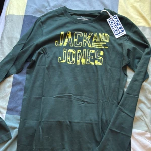 Jack & Jones långärmad t-shirt - Säljer tre långärmade t-shirts från Jack & Jones med coolt tryck i gult, orange och rött på bröstet. En är mörkgrön och två är marinblå. Perfekt för dig som gillar streetwear och snygga loggor. Materialet är mjuk bomull och passformen är normal.