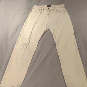 Beige jeans från Jack & Jones 28/32 - Snygga beige jeans från Jack & Jones i modellen Relaxed-Chris. De har klassisk femficksdesign, raka ben och normal passform. Tillverkade i bomull för en skön känsla och stilren look. Perfekta för dig som gillar en avslappnad vibe.