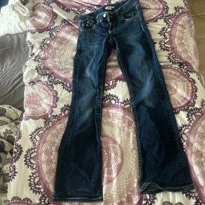 Blå bootcut jeans från Gina Tricot - Snygga blå jeans från Gina Tricot i modell bootcut med kontrastsömmar och klassiska fickor både fram och bak. Jeansen har normal passform och är tillverkade i jeansmaterial med en cool, mörk tvätt. Perfekta för dig som gillar retrovibbar och vill ha ett par stilrena jeans. Pris går att diskutera!