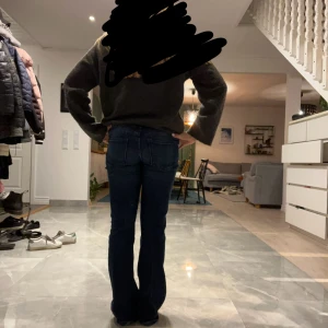 Mörkblå bootcut jeans med fickor - Snygga mörkblå jeans med bootcut passform och markerade sömmar framtill. Byxorna har två stora fickor fram och två bak, samt dubbla knappar i midjan. Perfekta för dig som gillar en klassisk men trendig look.