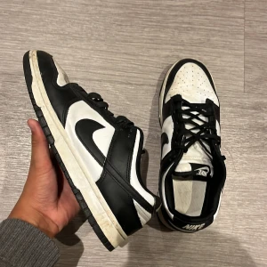 Nike Panda-Dunk low - Nike Dunk Low sneakers i svart och vitt med klassisk swoosh på sidan. Skorna har snörning, rund tå och platt sula. Ovandelen är i skinn och insidan är fodrad med textil. Perfekt för dig som gillar stilrena och ikoniska sneakers. Jag köpte de nya i USA för cirka 1300~