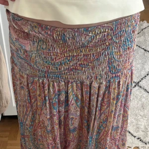 Färgglad långkjol - Säljer en bohemisk långkjol med paisleyinspirerat mönster i rosa, blått, gult och beige. Kjolen har smock i midjan och är tillverkad i ett mjukt, tunt bomullstyg som faller snyggt. Perfekt för dig som gillar färg och mönster. Skriv vid minsta fråga!💕💕