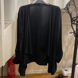 Svart loose kofta med knappdetalj - Svart, tunn och flowy kofta med loose passform. Långärmad med knappdetalj på ärmarna som ger en chill och avslappnad vibe. Materialet är mjukt och stretchigt, perfekt att slänga över en t-shirt eller linne. Enkel och stilren design VILA VLOTHES. 75kr frakt ej inklusive.