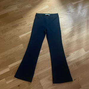Marinblåa bootcut byxor, storlek 150 - Snygga svarta bootcut byxor med hög midja och stretchigt material. De har en stilren look utan synliga detaljer och passar perfekt om du gillar en klassisk siluett med lite utsvängda ben. Perfekt för dig som vill ha en enkel men trendig stil.