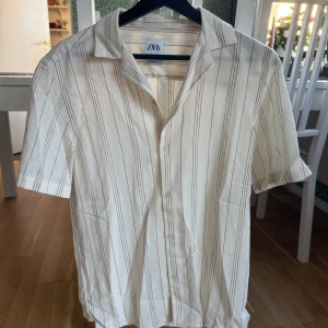 Randig skjorta kortärmad knappar zara - Randig skjorta kortärmad knappar. Köpt från Zara men aldrig använd 