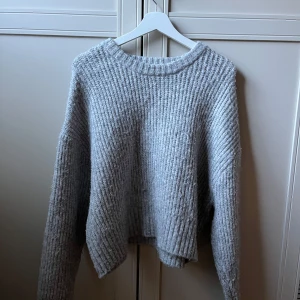 Grå stickad tröja från FB Sister - Mysig grå stickad tröja från FB Sister i storlek L. Tröjan har en ribbad struktur, rund hals och långa ärmar. Perfekt för kyliga dagar och enkel att matcha med jeans eller kjol. Snygg loose fit som ger en avslappnad vibe.