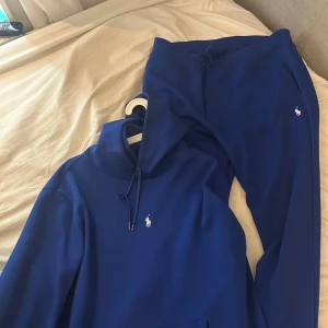 Blå mjukisbyxor från Ralph Lauren - Snygga blå mjukisbyxor från Ralph Lauren med klassisk vit logga på benet. Byxorna har dragsko i midjan och är gjorda i mjukt material som är perfekt för chill eller träning. Enkel och stilren design som passar till hoodie eller t-shirt.