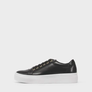 Svarta Vagabond sneakers i skinn - Snygga svarta sneakers från Vagabond med vit platt sula och guldfärgade metalldetaljer vid snörningen. Skorna är i skinn och har klassisk rund tå och svarta skosnören. Perfekta för en stilren och modern look. Skorna är ej använda!!🥰🥰🥰