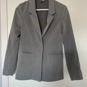 Grå kavaj från HM  - Stilren grå kavaj med klassisk krage och en knapp framtill. Två stora fickor framtill och raka ärmar ger en enkel och snygg look.  storlek xs 