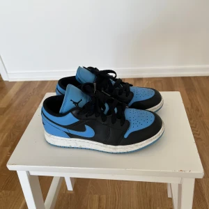 Nike Jordan 1 Low blå och svarta sneakers - Säljer ett par Nike Jordan 1 Low sneakers i blått och svart. Jättefina men används inte längre. 