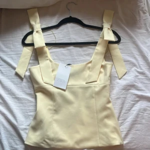 Ljusgul Zara topp rosett - Liten fläck på insidan men ej synlig när den är på! Skickar bild på fläcken privat om du vill. Från Zara!