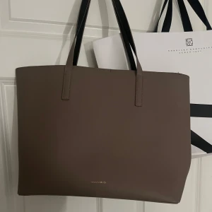 Brun axelväska från Anna Field - Snygg och stilren brun axelväska från Anna Field med minimalistisk design. Väskan har svarta handtag, magnetlås och ett stort huvudfack med innerficka med dragkedja. Perfekt för att bära med sig allt man behöver under dagen.