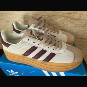 Adidas Gazelle  - Adidas Gazelle sneakers i beige mocka med vinröda detaljer. Tyvärr så är dem liiite för små för mig. Endast provade en stund hemma. Sulan är platå så perfekt för den som vill se lite längre ut! 1449 kr nypris. 