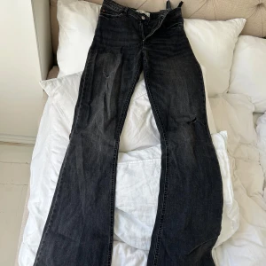 Svarta bootcut jeans från Zara - Säljer ett par svarta bootcut jeans från Zara med klassisk femficksdesign och dragkedja. Jeansen har en mörk tvätt och breda ben, vilket ger en snygg siluett. Perfekta för dig som gillar en avslappnad men trendig look.