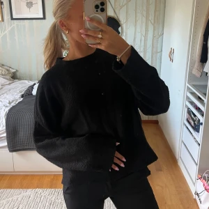 Svart stickad tröja från Zara - Mysig svart stickad tröja från Zara med loose fit och långa ärmar. Enkel design med rund halsringning och lite bredare ärmslut. Perfekt för lager-på-lager och chill dagar. Snygg till både jeans och kostymbyxor.