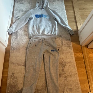 Grå HOODRICH hoodie med blå text - Säljer en grå hoodie från HOODRICH med blå broderad logga på bröstet. Tröjan har huva med snörning, magficka och långa ärmar. Mjuk bomullskänsla och relaxed fit, perfekt för chill dagar eller streetwear-stil. Priset går att förhandla!