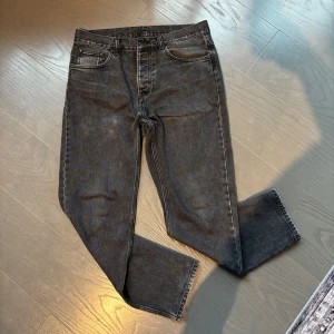 Carhartt Newel Pant svarta jeans - Säljer ett par svarta Carhartt Newel Pant i klassisk femficksmodell. Jeansen har rak passform, normal midja och är tillverkade i 100% bomull. Snyggt tvättad svart färg med diskreta slitningar och robust känsla. Perfekta för en avslappnad streetstil.