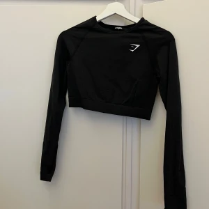 Träningströja  - Säljer denna snygga croppade träningströja ifrån Gymshark. Jag är lite osäker på storleken då jag klippt av lappen men det är antingen S eller M. Jag är en M och den sitter bra på mig. Bra skick🩷