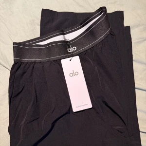 Svarta träningsbyxor från Alo Yoga - Alo yoga byxor, helt ny men är i den kortare modellen så tyvärr var den lite för kort för mig som är 170cm. Den passar perfekt en längd som är 155-162cm! 