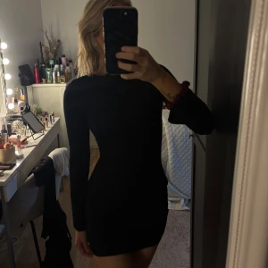 Svart ribbad kortklänning med lång ärm - Säljer en svart, figurnära kortklänning med lång ärm och ribbad struktur. Klänningen har en enkel, stilren design och är tillverkad i ett stretchigt material som sitter snyggt mot kroppen. Passar Xs/s 