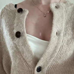 Beige stickad kofta från Selected Femme - Supermjuk och fluffig beige kofta från Selected Femme i storlek S. Koftan har stora mörka knappar framtill, ribbstickad struktur och en avslappnad passform. Perfekt att slänga över ett linne eller t-shirt för en chill look. Material: 39% ull, 24% polyester, 20% alpackaull, 15% nylon, 2% elastan (material-lappen inuti är bortklippt). Den är nopprig men går lätt att få bort med avnoppare. Inga andra defekter eller slitningar. Nypris: 600+