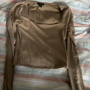 Beige långärmad topp från Amisu - Snygg beige långärmad topp från Amisu med fyrkantig halsringning. Tunn och mjuk i materialet, perfekt för att styla med jeans eller kjol. Enkel design utan mönster eller detaljer, ger en clean och modern vibe.