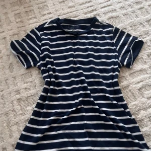 Randig marinblå t-shirt  - Snygg t-shirt från Primark i marinblått med vita horisontella ränder. Klassisk rund halsringning och korta ärmar. Regular fit-modell i mjuk bomull, perfekt för en chill och stilren look.