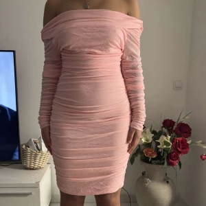 Rosa offshoulder klänning - Säljer en snygg rosa offshoulder klänning med långa ärmar i storlek M men passar även L. Klänningen har en tight passform och är perfekt för festliga tillfällen. Den är tillverkad i ett mjukt och bekvämt material som framhäver figuren. Använd en gång 