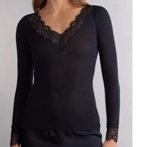 intimissimi svart långärmad topp med spetsdetaljer - jättefin elegant svart topp med v-ringning och spetsdetaljer vid hals och ärmslut. perfekt för en stilren look, från intimissimi 💕