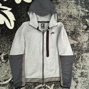 Grå och svart hoodie från Nike - Snygg sällsynt grå och svart nike tech finns uppe för 1900 på no sauce the plug. Storlek S. I bra använd skick. Små defekt som ej syns.