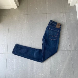 Blå jeans från Replay - Snygga blå jeans från Replay i modellen Anbass. De har en klassisk femficksdesign och en bekväm passform. Perfekta för en stilren look.