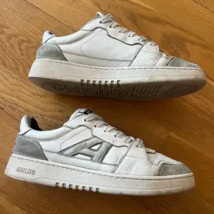 Vita Eytys sneakers med grå mockadetaljer, storlek 40 men passar även 41. Skicket framgår av bilderna – de är lite slitna på insidan av hälen, därav sitter det inlägg över för att dölja slitaget och öka komforten. Trots dessa estetiska defekter, behåller skorna fortfarande en snygg och stilren look när de bärs