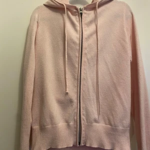 Ljusrosa hoodie med dragkedja - Säljer en ljusrosa hoodie med dragkedja och huva. Tröjan har långa ärmar och ribbade muddar vid ärmslut och nederkant. Perfekt för en avslappnad stil. Koftan är i jätte fint skick i storlek S den är från lager 157!