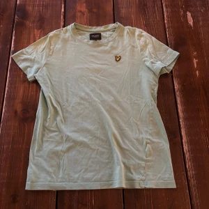 Grön t-shirt från Lyle & Scott - Säljer en stilren grön t-shirt från Lyle & Scott med korta ärmar och ett broderat emblem på bröstet. Perfekt för en avslappnad look. 💚tveka inte att höra av dig vid frågor! Storleken är junior men jag skulle säga att den absolut passar Xs och kanske S