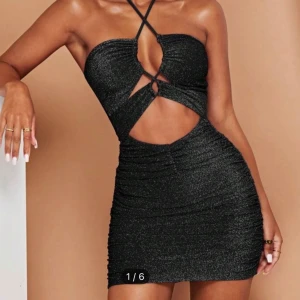 Svart glittrig klänning - Snygg svart klänning med glittrande detaljer och smala axelband. Klänningen har en åtsittande passform och en elegant snörning framtill. Perfekt för en kväll ute eller en speciell tillställning.Testat den men aldrig haft på mig den någonstans.Den var för liten för mig.