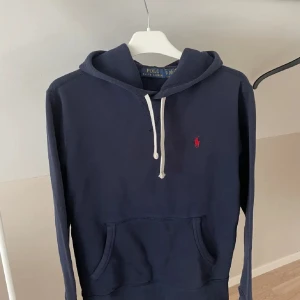 Ralph Lauren hoodie - Säljer en stilren mörkblå hoodie från Ralph Lauren, tröjan har inga defekter alls och är i super fint skick. Bara att höra av sig vid intresse eller frågor!