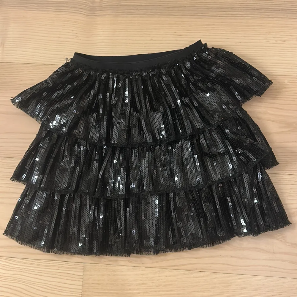 Snygg svart kjol från Zara täckt med glittrande paljetter. Kjolen har flera lager av volanger. Jag som är runt 168 kan ha kjolen så den är stor i storlek . Hameet.