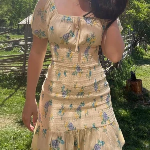 Gul blommig sommarklänning - En otroligt fin klänning i en gul färg med vackra blåa blommor, får lite Urban outfitters känsla från den men den är ifrån bikbok💐 Står storlek M men tror mer att den passar xs/s då storleken är lite liten💐 Vid mer frågor eller bilder kontakta oss!💕🫶