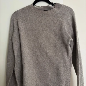 Beige stickad tröja med rund hals - En stilren beige stickad tröja med rund halsringning och långa ärmar. Tröjan har en mjuk och skön känsla, perfekt för lager-på-lager och passar till allt. Ribbstickade muddar vid hals, ärmslut och nederkant ger en snygg finish.