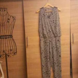 Svartvit mönstrad byxdress från Vila - Säljer en snygg byxdress från Vila i storlek S. Byxdressen är svartvit med ett coolt blommigt mönster, har ärmlös design och resår i midjan för skön passform. Perfekt för dig som gillar unika plagg med lite edge.