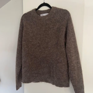 Brun stickad tröja från Zara - Mysig brun stickad tröja från Zara i storlek S. Tröjan har en klassisk rund halsringning och långa ärmar. Fint skick! Den ska vara lite ”hårig” 💕