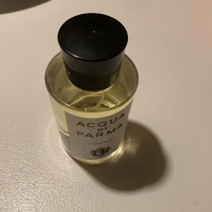 Acqua di Parma Colonia parfym - Klassisk parfym från Acqua di Parma, Colonia. Flaskan är cylindrisk i genomskinligt glas med svart plastkork och vit etikett med svart text. Innehållet är ljusgult. En tidlös och elegant doft som känns lyxig och stilren.