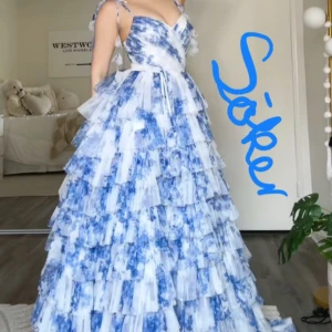 SÖKER Blåvit volangklänning med axelband - Söker en sån klänning från JJ House eller liknande. Drömmig långklänning i blått och vitt med volanger i flera lager och smala axelband. Klänningen har v-ringning och ett romantiskt, flowy uttryck. Perfekt för dig som vill sticka ut med en unik och somrig look.