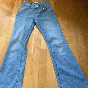 Blå bootcut jeans från Lindex, 158 - Snygga ljusblå jeans från Lindex i bootcut, midwaist och tillverkade i mjukt bomullsjeans. Perfekta för dig som gillar en retro vibe. En liten gräs fläck på knät. 