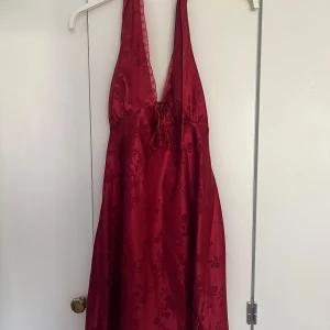 Röd halterneckklänning Miss Selfridge - Supersnygg röd kortklänning från Miss Selfridge i glansigt material. Halterneck-modell med öppen rygg. Klänningen är i nyskick! 